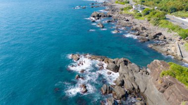 Issız uçurumun tepesine tünemiş, berrak derin mavi denize bakan.