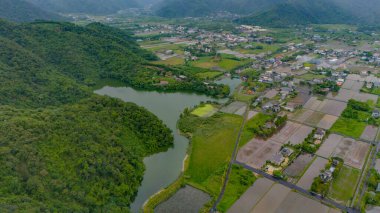 Bereketli yeşil tepeler ve köy cazibesiyle sarılmış sakin bir göl.