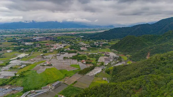 Idyllic kırsal arazisi uzak şehir ve dağlarla harmanlanmış kasvetli bir gökyüzü altında