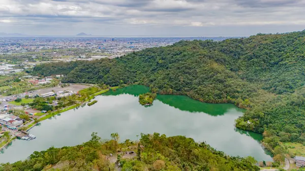 Meihu Gölü 'nün sakin yansımaları yemyeşil ve uzak şehir siluetinin ortasında