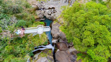 Turkuvaz suları ve yemyeşil yemyeşil bir vadi üzerindeki cam gözlem güvertesinin manzarası.