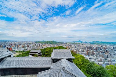 Geleneksel Japon şatosu çatıları genişleyen modern bir şehre bakıyor. Tarihi ve kentsel panorama.