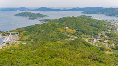 Bereketli yeşil tepeler sakin bir iç denize iniyor. Adalar ve kıyı kasabaları manzarayı noktalıyor.