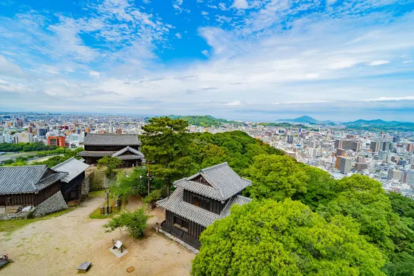 Tarihsel Japon şatosu yapıları genişleyen modern bir şehri gözden kaçırır. Sonsuz manzara, mavi gökyüzü.