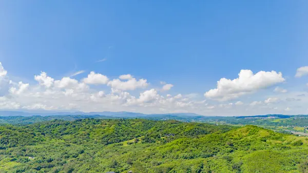 Bulutlarla kaplanmış mavi gökyüzünün altında dalgalanan orman tepelerinin hava manzarası Tayvan 'ın yaz manzarasının huzur verici güzelliğini gözler önüne seriyor..