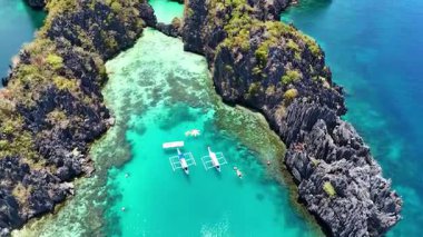 Gemiler kayalarla çevrili açık sığ sularda demirli.