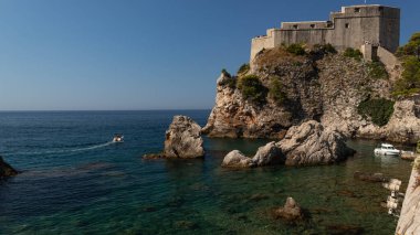 Lovrijenac Kalesi 'nin büyüleyici manzarası, Tvrdava Lovrijenac Dubrovnik Körfezi' nin üzerinde ihtişamlı bir şekilde yükseliyor, ön planda parlak mavi deniz var..