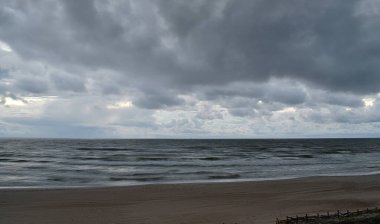 Deniz Burnu. Dalgalı Baltık Denizi ve kum bulutları altında kumlu kıyı.