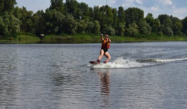 Genç bir kadın nehirde wakeboard sürmeyi öğreniyor..