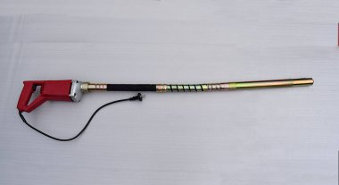 Electric vibrating machine for compacting concrete on a gray background.