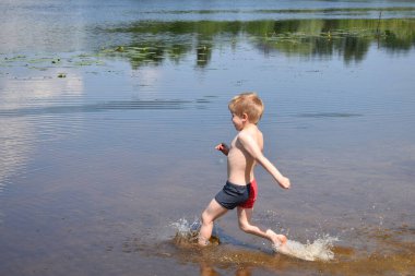 Çocuk sahilde suya koşuyor..