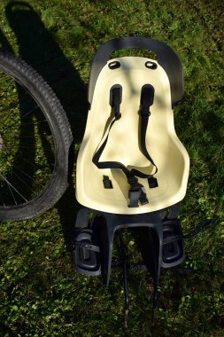 Bisikletin yanındaki çimenlikte çocuk bisikleti koltuğu..