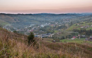 Tren, dağ demiryolu köprüsünde. Gün batımında dağ manzarası.