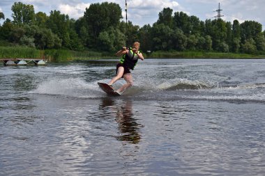 Bir adam nehirde wakeboard sürmeyi öğreniyor..