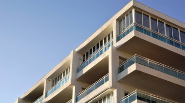 corner of modern minimalist building with windows and balconies against the sky