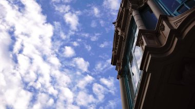 Bulutları yansıtan evin ön cephesindeki düşük açılı pencere.
