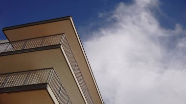 Bulutlu gökyüzüne karşı balkonlu bina cephesinin alçak açısı