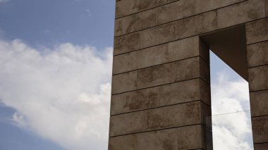 Bulutlu gökyüzüne karşı geometrik açıklıklarla duvar cephesi