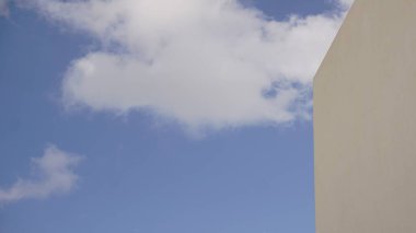 Arkaplan olarak mavi bulutlu gökyüzüne karşı beyaz duvar