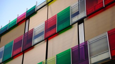 Modern bir binanın ön cephesinde renkli cam korkuluklar.