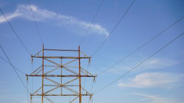 Mavi gökyüzüne karşı yüksek voltajlı elektrik kulesi