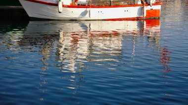 Tahta kırsal balıkçı teknesinin dalgalanan suyundaki yansıma