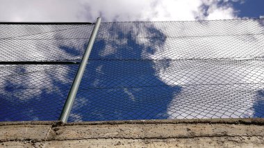 Bulutlu gökyüzüne karşı metal parmaklıkların düşük açısı