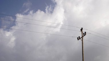 electric pole against cloudy sky