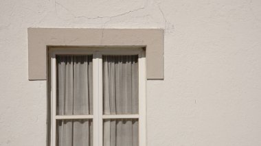 Beyaz duvarda perdeleri olan çift tahta pencere.