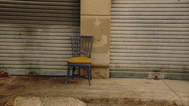 Kapalı panjurların önündeki eski sandalye