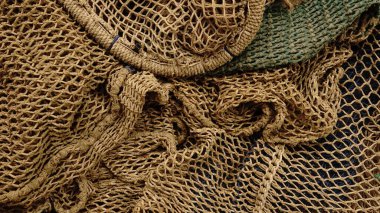 Eski balık ağlarının kabataslak dokuları ve toprak tonlarıyla iç içe geçmiş ipleri ve dokuma desenlerini gösteren detaylı bir görünümü var..