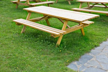 Yeni boş çam ağacından piknik masası halka açık bir parkta yeşil bir çayırda.