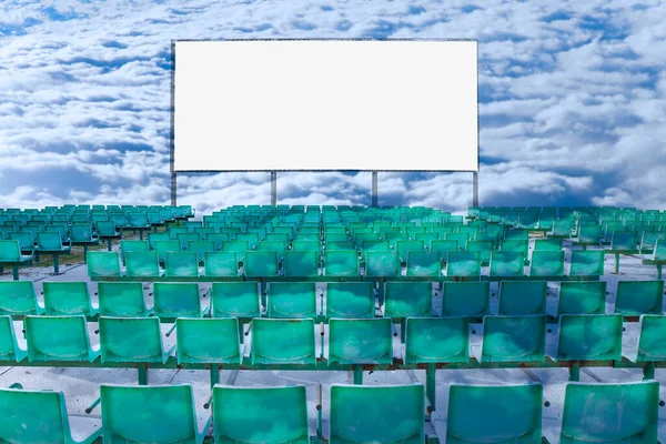 Outdoor cinema with chairs and white projection screen on cloudy sky background - concept image