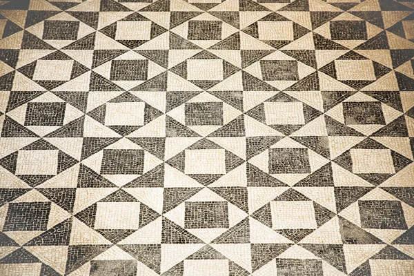 Ancient Italian Roman mosaic floor with triangular shapes composed of small white and black stone pebbles