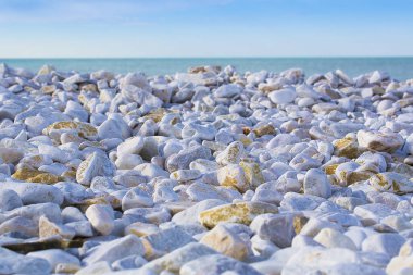 Beyaz ve gri taşlar, denizin üzerinde ufuk çizgisi olan deniz suyundan yavaşça yuvarlanmış ve yıkanmış.