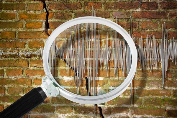 Earthquake wave graph concept with cracked and damaged brick wall and magnifying glass
