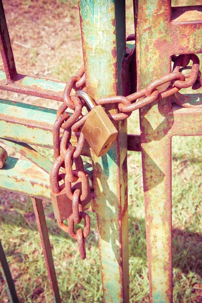 Rusty metal gate closed with padlock - concept image