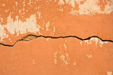 Deep horizontal crack in an old wall with damaged plaster 