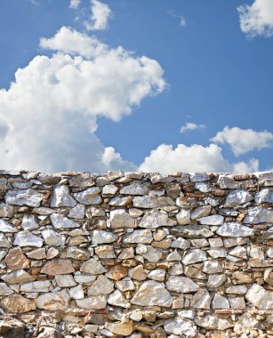 Stone wall with large stone blocks against a sky background - image with copy space.