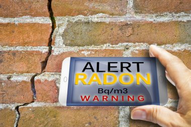 Radyoaktif gaz radonunu izlemek için taşınabilir bilgi aygıtı - çatlak bir duvara karşı konsept görüntüsünü test etmek için radon.