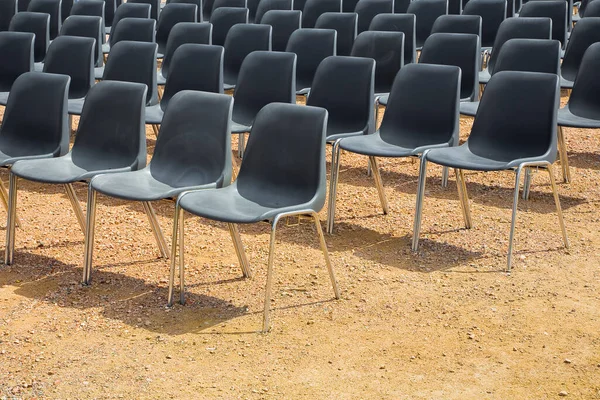 Outdoor cinema with black plastic chairs in a row in a gravel floor