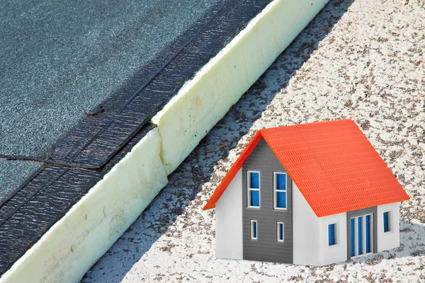 Roof thermal insulation with polystyrene panels covered with waterproof membrane under a concrete screed to improve the energy efficiency of the building - concept with home model