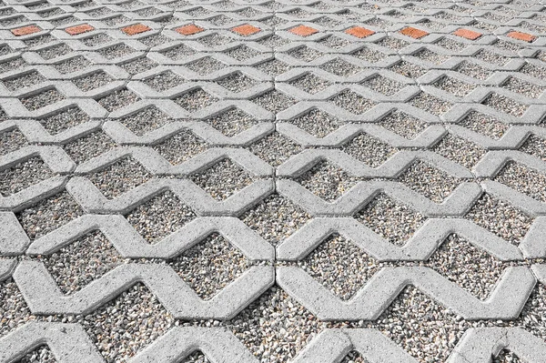 Concrete self locking tiled and draining flooring blocks assembled on a substrate of sand with gravel - type of flooring permeable to rain water as required by laws used in car parking areas