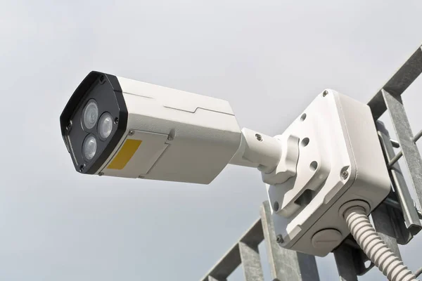 Security Camera against a metal grid for the security control of urban spaces