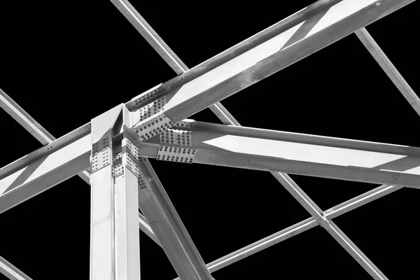 Detail of a new precast steel structure with pillars, steel beams and bolts in galvanized steel against a black background