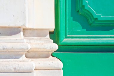 Beyaz mermer bir duvara karşı boyanmış yeşil ahşap bir kapının ayrıntıları.