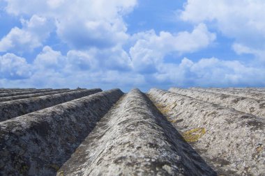 Eski, eğri büğrü asbest panellerden yapılmış çatı - binalarda ve inşaat sektöründe tehlikeli malzemeler