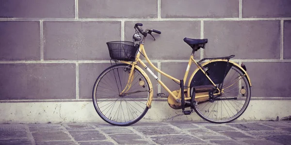 石で舗装されたイタリアの通りの石膏壁に対する古い錆びた女性の自転車 — ストック写真