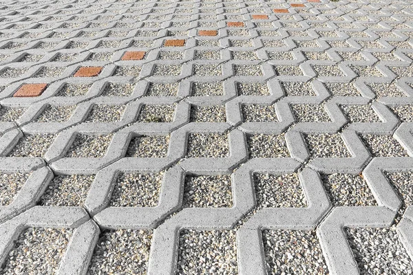 Concrete self locking tiled and draining flooring blocks assembled on a substrate of sand with gravel - type of flooring permeable to rain water as required by laws used in car parking areas