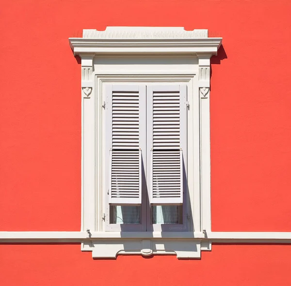 stock image Old neoclassical italian window with wooden shutter against a red colored plaster wall - Italy